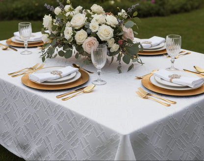 Valence quilted white tablecloth with interlocking fret pattern, set with gold chargers and crystal